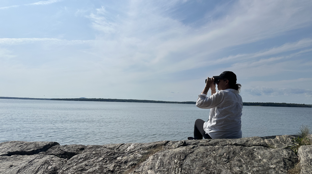Woman sitting on rock at ocean.